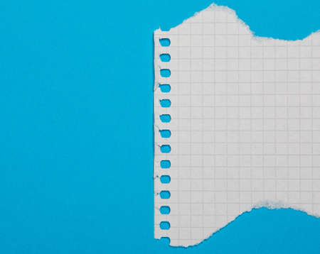 Torn piece of checkered paper on blue backgroundの写真素材