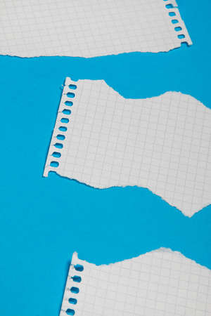 Torn pieces of checkered paper on blue backgroundの写真素材
