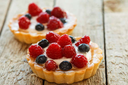 Cup of coffee and sweet cakes with berries on wooden tableの写真素材