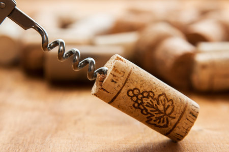 Corkscrew and corks on wooden table