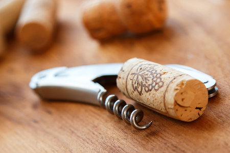 Corkscrew and corks on wooden table