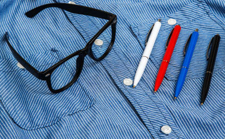 Blue shirt, eyeglasses and colorful pensの写真素材