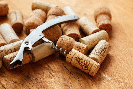 Corkscrew and corks on wooden table