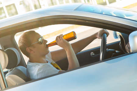 Drunk man is drinking beer in his carの写真素材