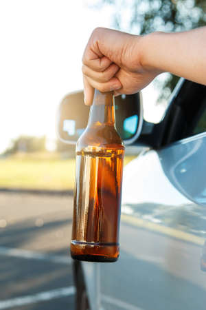 Car driver is holding a bottle of beer in his handの写真素材