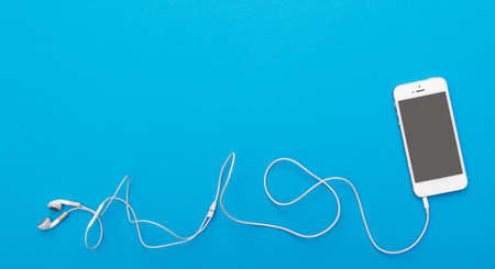 Smart phone and earphones on blue backgroundの写真素材