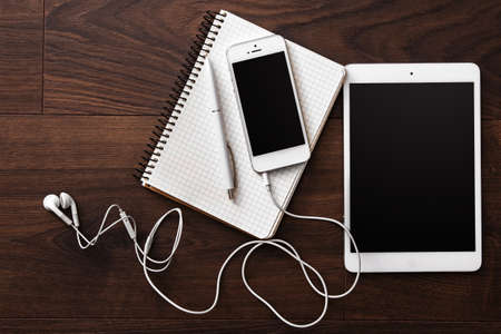Smartphone and tablet with earphones on wooden surfaceの写真素材