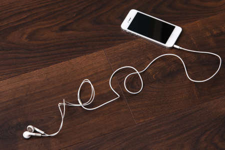 Smart phone and earphones on wooden surfaceの写真素材