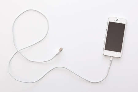 Smartphone and cable on white backgroundの写真素材