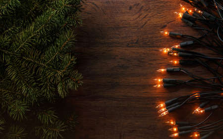 Christmas lights and branches of spruce on wooden surfaceの写真素材