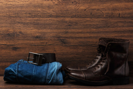 Leather boots, jeans and belt on wooden surfaceの写真素材