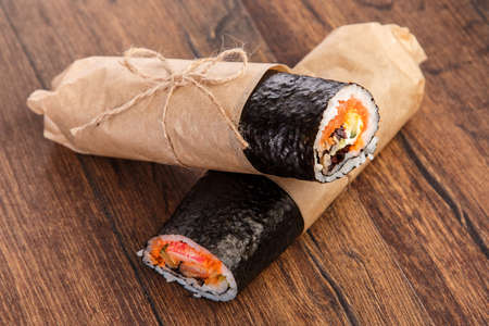 Sushi burrito - new trendy food concept. Sushi burrito rolls on wooden surfaceの写真素材