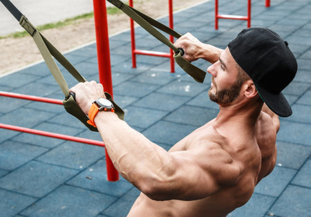 Man during workout with suspension straps on the street