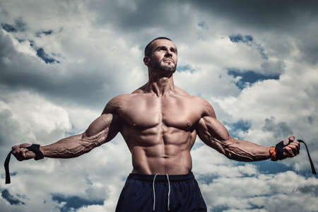 Muscular man posing under cloudy skyの写真素材
