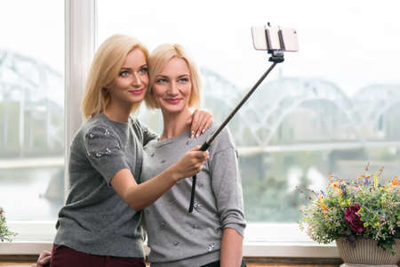 Mother and daughter taking a selfie at homeの写真素材