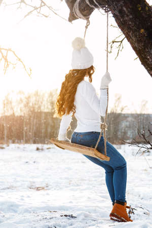 Happy girl on rope swing at sunny winter dayの写真素材