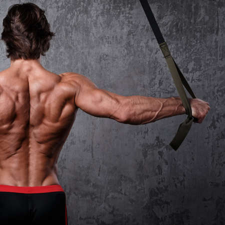 Muscular man during workout with suspension strapsの写真素材
