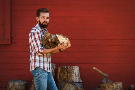 Handsome bearded man is holding firewoodsの写真素材