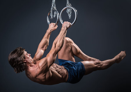 Strong and muscular gymnast guy on the rings