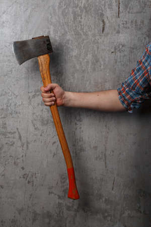 Axe in male hand over old dirty wallの写真素材