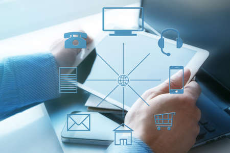 Hands with a tablet and different icons around. Omni channelの写真素材