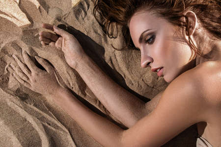 Beautiful woman lying on the sandの写真素材