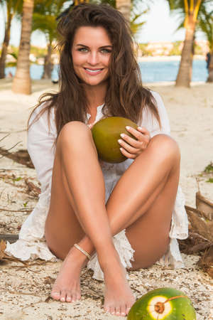Beautiful woman and lot of coconuts on the groundの写真素材