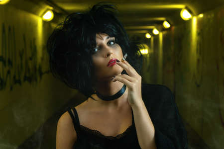 Freaky woman with black hair smoking a cigarette  in the dark undergroundの写真素材