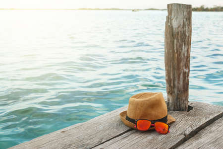 Straw hat and sunglasses on the wooden pierの写真素材