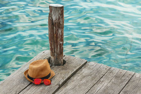 Straw hat and sunglasses on the wooden pierの写真素材