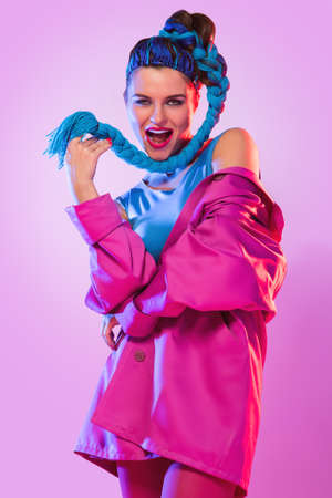 Stylish woman in colorful clothes with threads in her tail over pink backgroundの写真素材