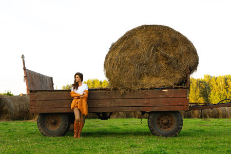 Lovely young woman and  carriage with a haystacks in the village