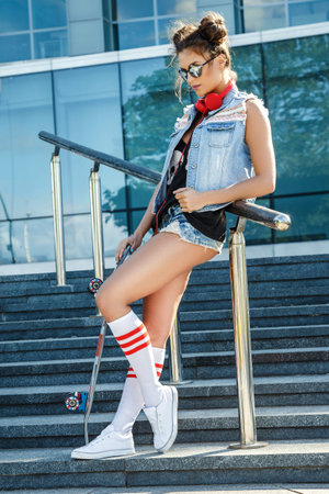 Stylish girl with a skateboard on the street