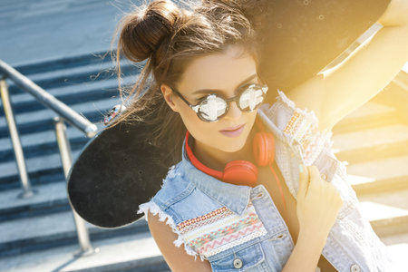 Portrait of stylish girl with a skateboard on the street