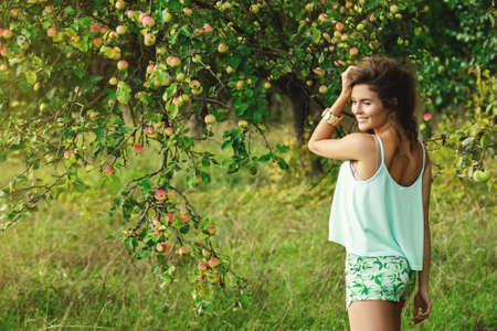 Beautiful, young and happy woman in garden during a picking applesの写真素材
