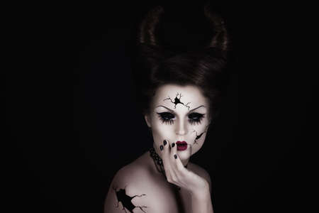Model in creative image. Talking broken doll with horns on her head.の写真素材
