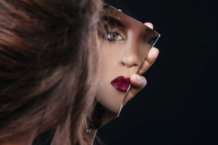 Beautiful woman looking in the piece of mirrorの写真素材