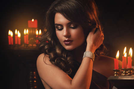 Beautiful woman in the dark room with a lot of candlesの写真素材