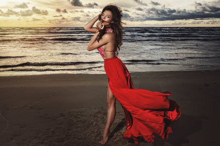 Stunning woman in beautiful red dress on the seaside