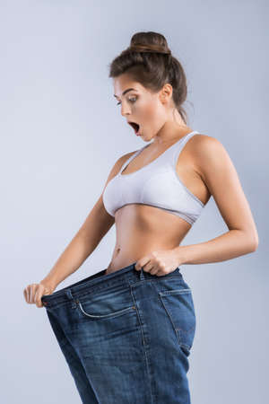 Happy woman after weight-loss is try her old jeansの写真素材