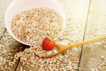Oatmeal flakes with strawberry and wooden spoon