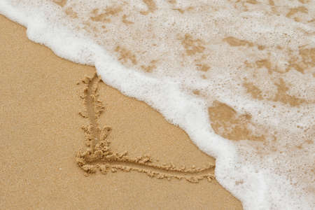 Drawing of a heart on the sand and wave with foamの写真素材