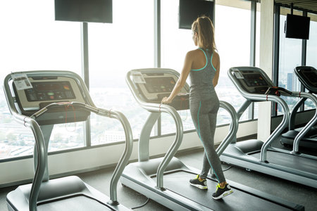 Young and sporty woman on treadmill in the gym
