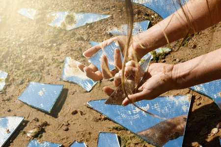 Female hands and lot of broken mirror shardsの写真素材