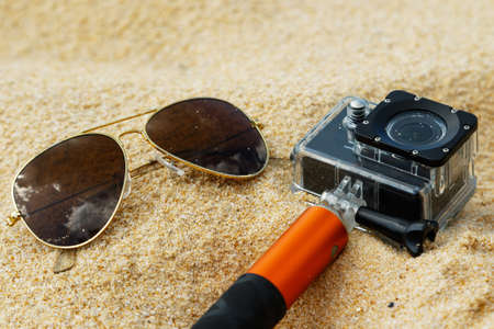 Sunglasses and action-cam on the sandの写真素材