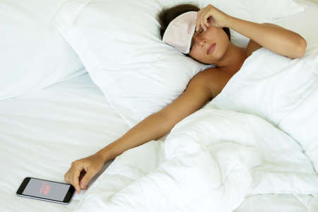 Sleepy woman looking on smartphone and don't want to wake upの写真素材