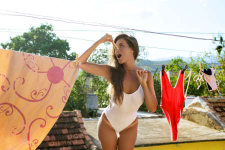 Beautiful woman and wet swimsuits on the roofの写真素材