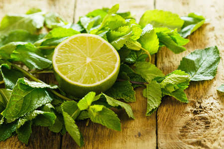 Mint leaves and lime on wooden tableの写真素材