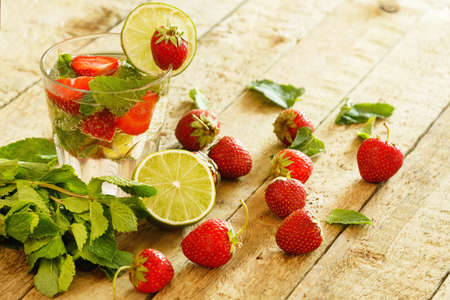 Refreshing drink with strawberry, lime and mint on wooden tableの写真素材