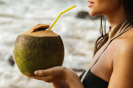 Woman with a coconut drink on the beachの写真素材